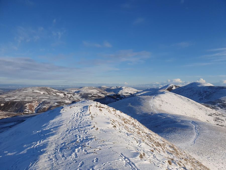 A snow-covered ridge in the Pentland Hills under a clear blue sky.